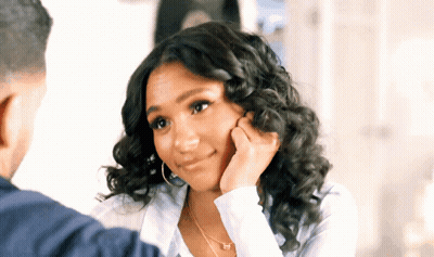 Curly-Haired Woman Touching Face Man Looks On GIF
