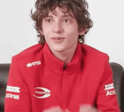 Curly Haired Young Man In Red Jacket With Sponsors GIF