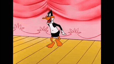 Daffy Duck Is Dancing On A Stage With A Pink Curtain Behind Him . GIF