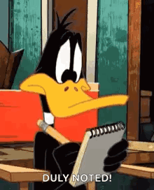 Daffy Duck Is Sitting At A Table Holding A Notebook And A Pen . GIF