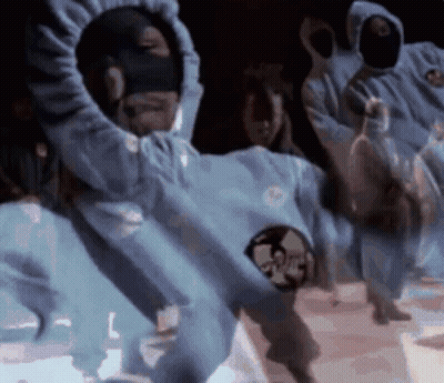 Dancing People In Hooded Sweatshirts And Masks In Dark Room GIF