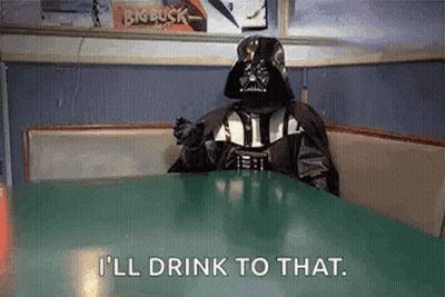 Darth Vader Is Sitting At A Table With A Drink In His Hand . GIF