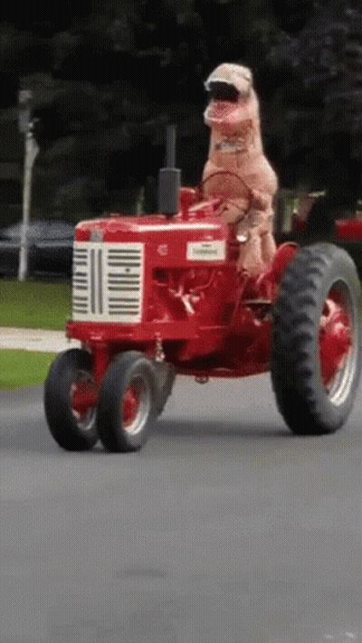 Dog In T-Rex Costume Driving Red Farmall Tractor GIF
