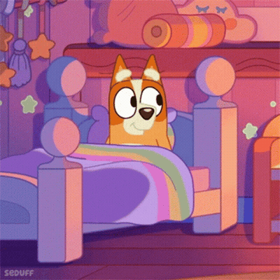 Dog Lying In Bed With Rainbow Blanket GIF