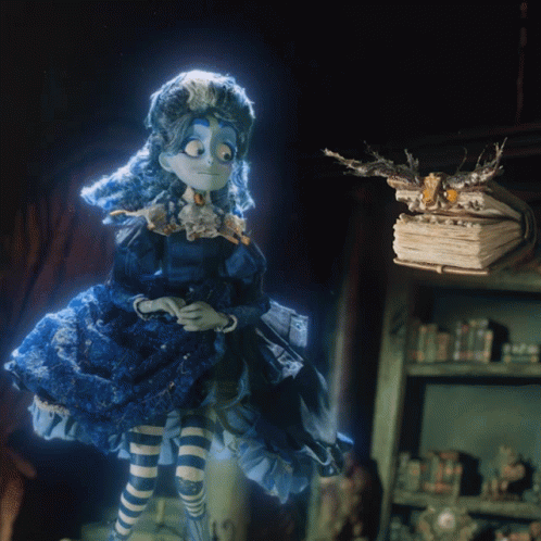 Doll In Blue Dress Next To Pile Of Books GIF