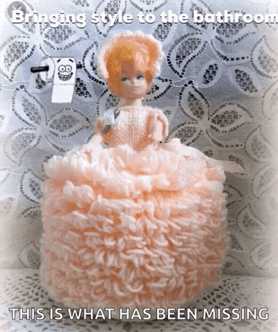 Doll In Pink Dress Sitting On Toilet Paper Caption Bringing Style To The Bathroom GIF
