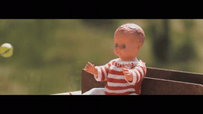 Doll In Red And White Striped Shirt Playing With Tennis Ball In Front Of Experiment Sign GIF