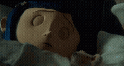 Doll Laying On Bed With Blue Nail Polish On Nose GIF