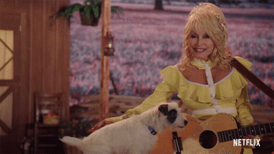 Dolly Parton Is Holding A Guitar Next To A Small Dog GIF