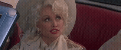 Dolly Parton Is Sitting In The Back Seat Of A Car Wearing A White Hat And A White Shirt . GIF