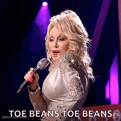 Dolly Parton Singing Into A Microphone With The Words Toe Beans Toe Beans Behind Her GIF