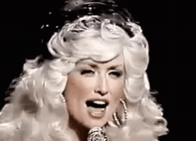 Dolly Parton Singing Into Microphone With Wig And Earrings GIF