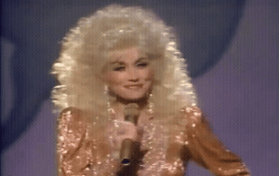 Dolly Parton Smiling At Microphone On Stage GIF