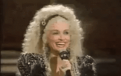Dolly Parton Smiling Holding Microphone In Wig GIF