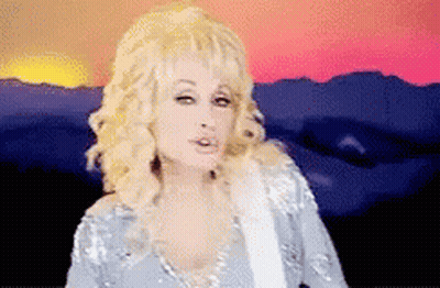 Dolly Parton Standing In Front Of Sunset Holding Guitar GIF