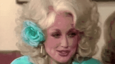 Dolly Parton Wearing Wig With Flower In Ear GIF