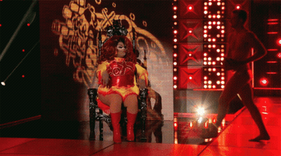 Drag Queen Sitting On Throne With Man Behind GIF