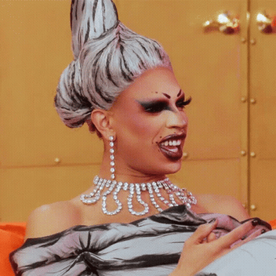 Drag Queen Wearing Pearls And Earrings GIF