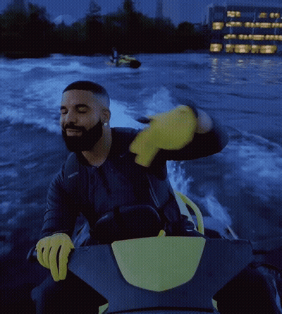 Drake Is Riding A Jet Ski In The Water With A Yellow Glove On GIF