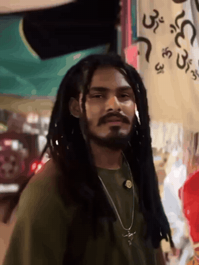 Dreadlocked Bearded Man Near Arabic Sign GIF