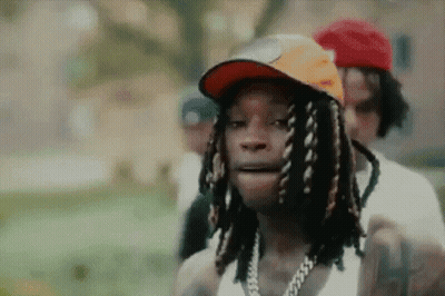 Dreadlocked Man In Hat And Chain Beside Another GIF