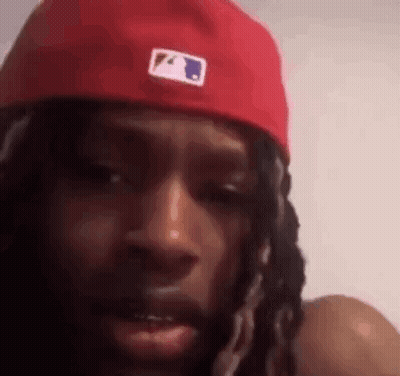 Dreadlocked Man With Red Hat Looking At Camera GIF
