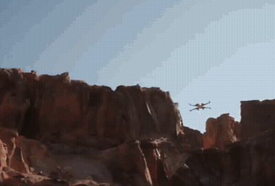 Drone Flying Over Rocky Cliff Blue Sky GIF