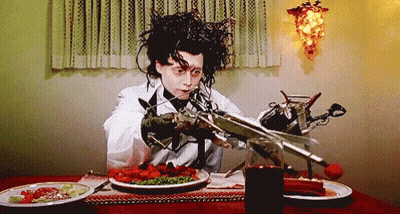Edward Scissorhands Is Sitting At A Table With Plates Of Food GIF