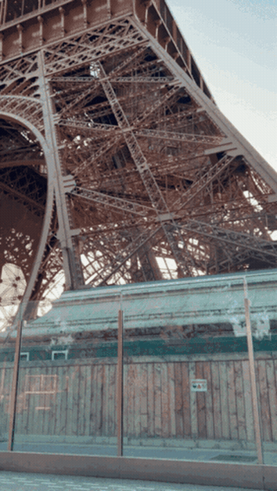 Eiffel Tower Behind Glass Fence And Wooden Wall GIF
