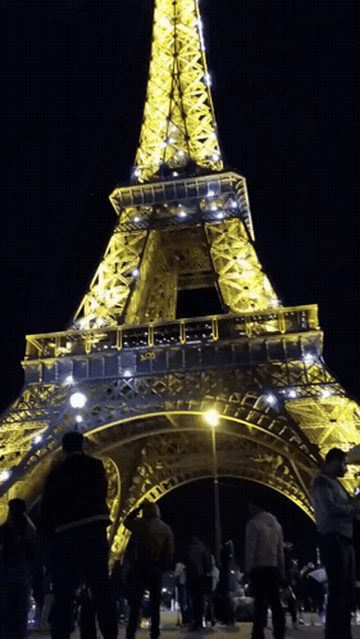 Eiffel Tower Lit Up At Night Surrounded By People GIF