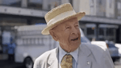 Elderly Man In Straw Hat And Tie Standing On Street GIF