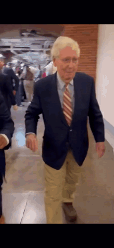 Elderly Man in Suit and Tie Walking Down Hallway