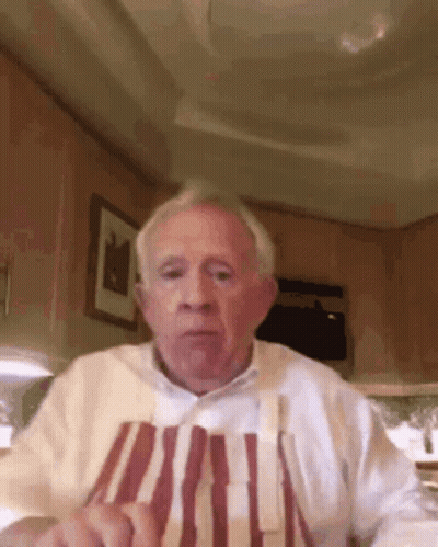 Elderly Man Sitting At Table In Apron GIF