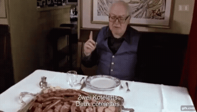 Elderly Man Sitting At Table With Food And Meat Tray GIF