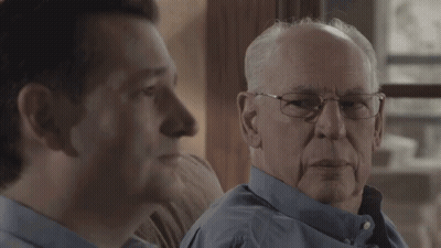 Elderly Man With Glasses Sitting On Couch With Another Man GIF