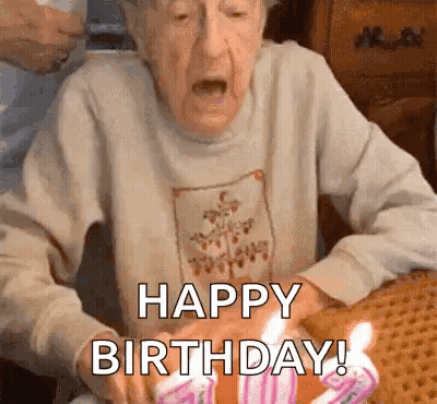 Elderly Woman Blowing Out Birthday Candles Saying Happy Birthday GIF