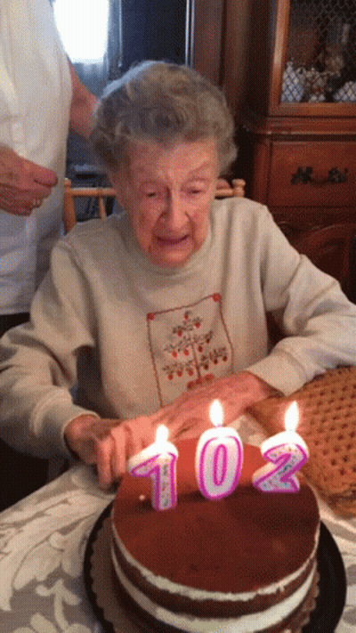 Elderly Woman Blowing Out Candles On 102 Cake GIF