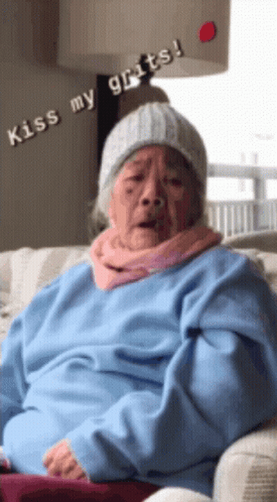 Elderly Woman In Beanie And Blue Sweater Says Kiss My Grits GIF
