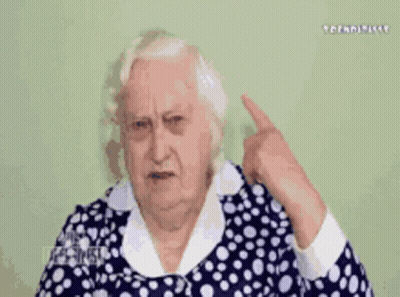 Elderly Woman In Blue And White Polka Dot Dress Covering Ear GIF