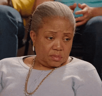 Elderly Woman In Blue Shirt And Gold Necklace GIF