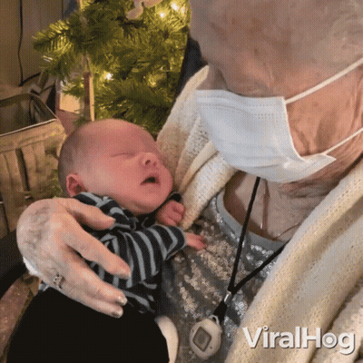 Elderly Woman In Face Mask Holding Baby GIF