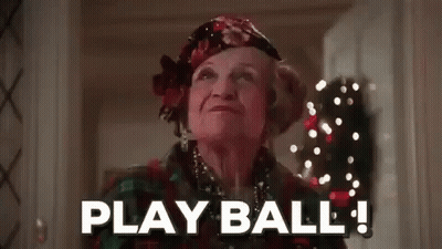 Elderly Woman In Hallway With Christmas Tree Says Play Ball GIF