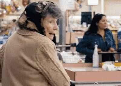 Elderly Woman In Head Scarf Standing In Store GIF