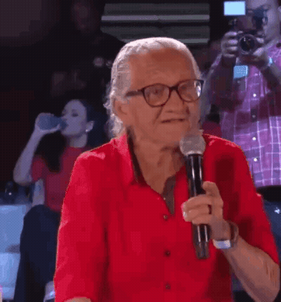 Elderly Woman In Red Shirt Holding Microphone GIF