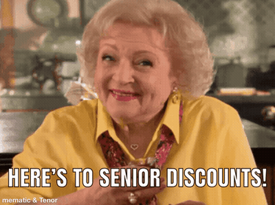 Elderly Woman In Yellow Shirt Says Here's To Senior Discounts GIF