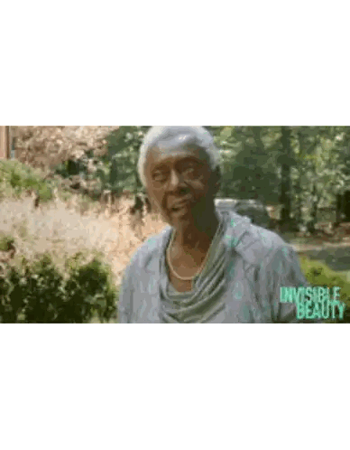 Elderly Woman Standing Before Bush With Invisible Beauty Sticker
