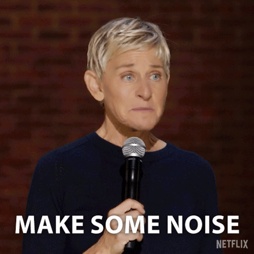 Ellen Degeneres Holds A Microphone In Front Of A Brick Wall And Says Make Some Noise GIF