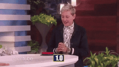 Ellen Degeneres Is Sitting At A Table With A Button That Says 1.0 On It GIF