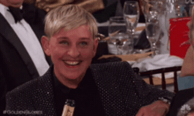Ellen Degeneres Is Smiling While Sitting At A Table GIF