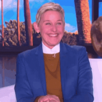 Ellen Degeneres Is Smiling While Sitting On A Couch In Front Of A Window . GIF